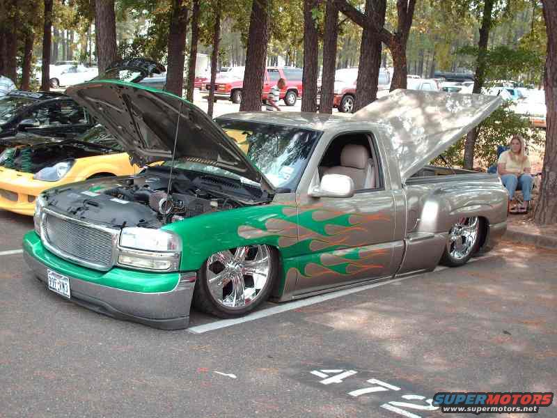 Green and silver pickup truck with flames, hood open, lowered on chrome wheels