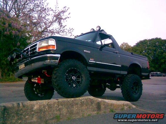 Black 1995 Ford Bronco lifted with large tires, seen from a 3/4 front angle