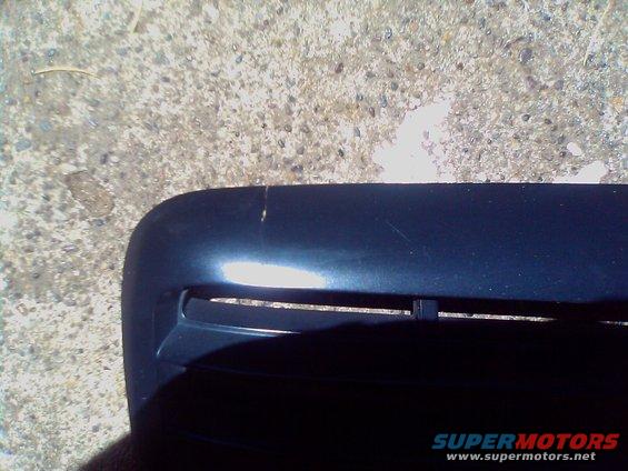 Close-up of a dark blue car grille with horizontal slats. Some scratches are visible on the upper surface