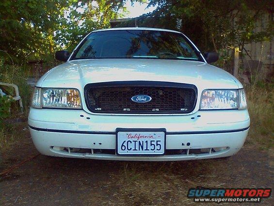 Front view of a white 2000 Ford Crown Victoria grille with a California license plate