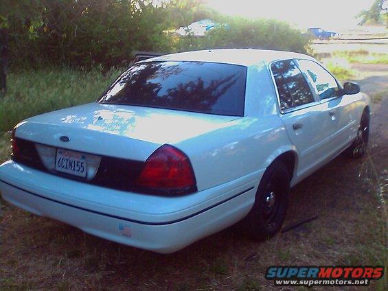 White 2000 Ford Crown Victoria sedan, rear view, parked on grass. License plate reads 6CIN155