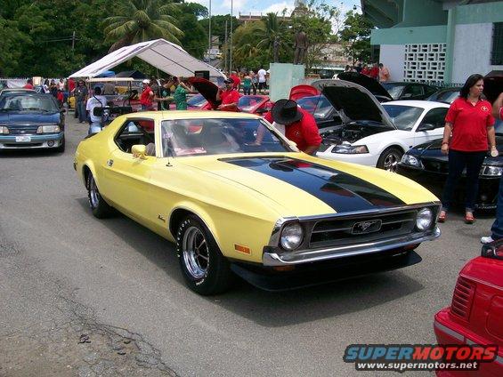 Yellow 1971 Ford Mustang coupe with black racing stripes, front quarter view, parked outdoors