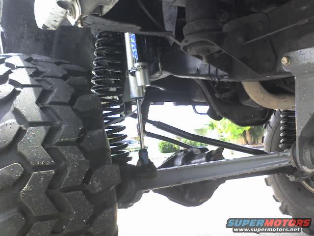 Close-up of a large off-road tire and suspension components, including a shock absorber and coil spring