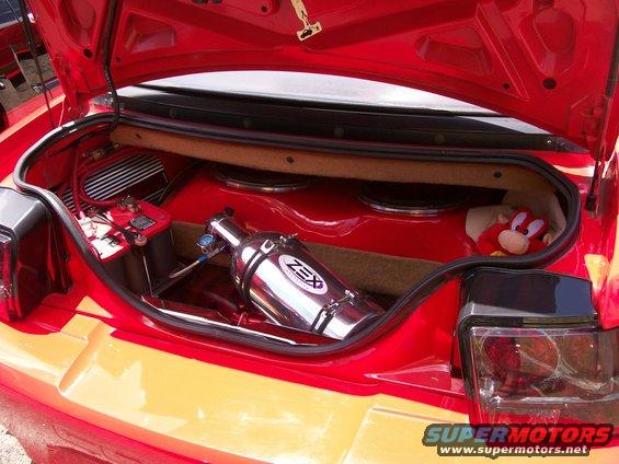 Red car trunk interior with a ZEX nitrous bottle, battery, and speakers