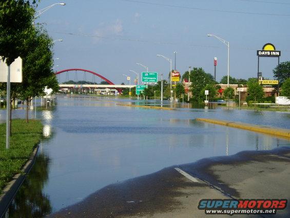 Flooded road with a red arched bridge in the distance and a Days Inn sign