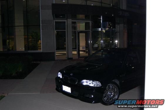Black 2002 BMW M3 parked in front of a modern building at night