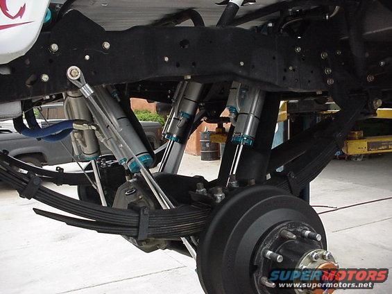 Close-up of heavy-duty suspension with multiple shocks and leaf springs