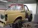 1996 Ford Bronco - A 1996 Ford Bronco is in a body shop, covered in primer and plastic sheeting, ready for repair work.