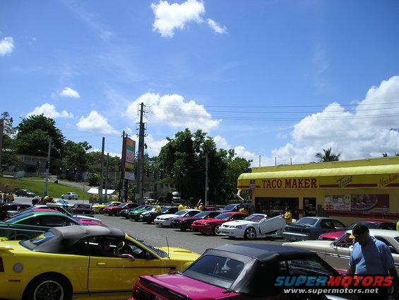 Yellow 2001 Ford Mustang convertible parked in front of Taco Maker with other Mustangs