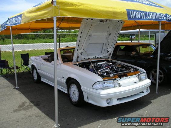 White convertible with hood open, showing engine. White wheels and body kit. Tan interior visible