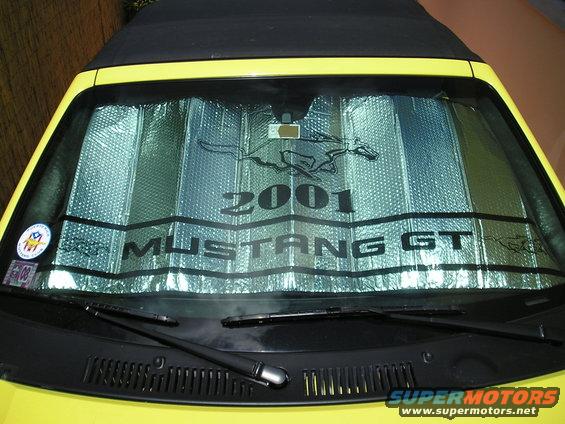Yellow convertible Mustang GT with a sunshade displaying '2001 Mustang GT' and a running horse logo