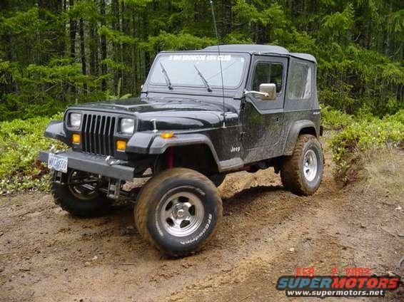 Black 1995 Jeep Wrangler on a dirt trail with trees in the background
