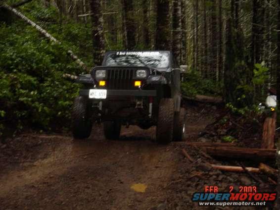 1995 Jeep Wrangler driving on a muddy forest trail