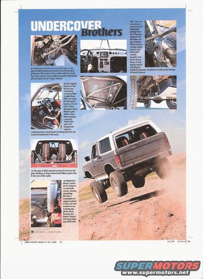 Ford Bronco driving up a dirt hill, kicking up dust. It has a roll cage inside and spare tires in the back