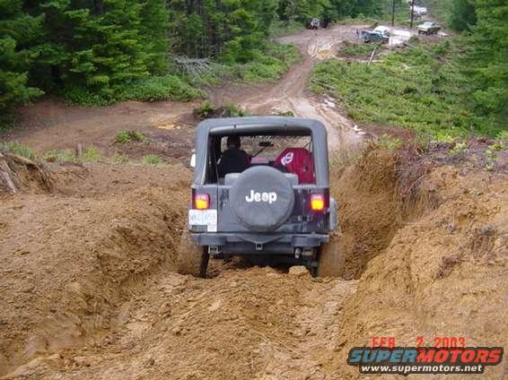 Jeep Wrangler driving through mud, another vehicle visible in background