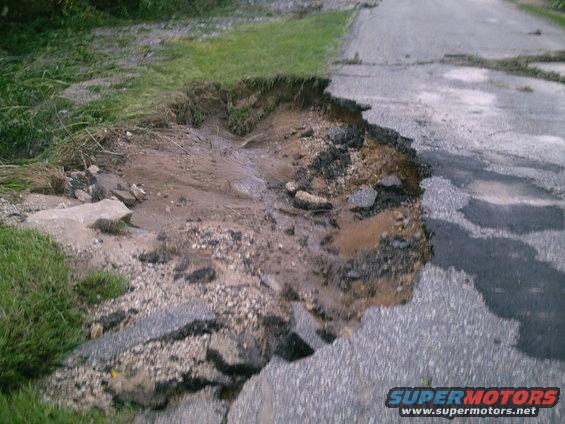 Roadside erosion with water runoff and damaged asphalt