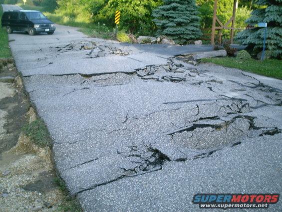 Black van on a road that's cracked and sinking