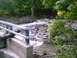2001 Dodge 2500 - A creek flows rapidly over rocks, with debris washed up on the banks and a bridge railing in the foreground.