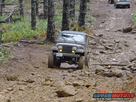 Gray 1995 Jeep Wrangler on a rocky trail. Text on windshield