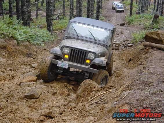 Gray 1995 Jeep Wrangler navigating a muddy off-road trail