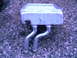 1987 Ford Bronco II - Heater core part with two metal tubes, resting on a gravel surface.