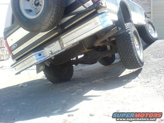 1985 Ford Bronco rear bumper and spare tire mounted on the tailgate, angled on a gravel incline