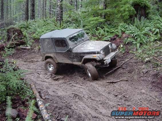 Black 1995 Jeep Wrangler navigating a muddy forest trail