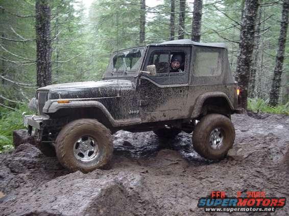 Muddy Jeep Wrangler driving over rocks and dirt on a trail