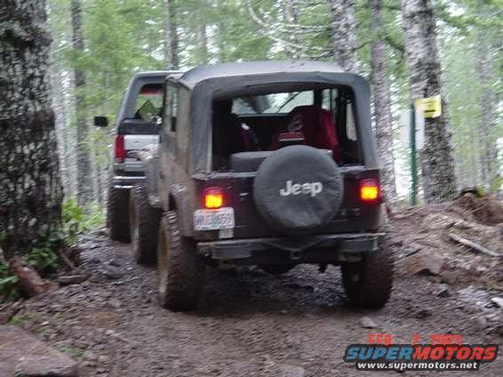 1995 Jeep Wrangler on a dirt trail with another vehicle behind it