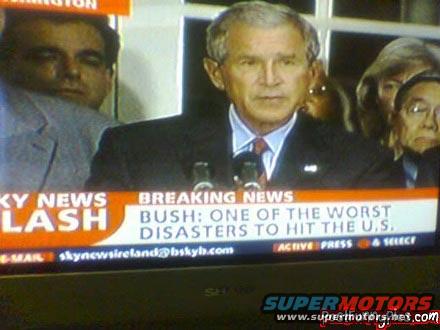 George W. Bush speaking at a podium with 'BREAKING NEWS BUSH: ONE OF THE WORST DISASTERS TO HIT THE U.S.' displayed on a chyron