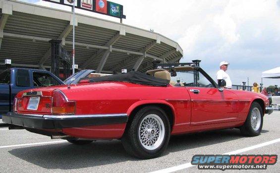 red convertible Jaguar parked next to a blue pickup truck in front of stadium seating