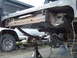 1979 Ford Bronco - The underside of a 1979 Ford Bronco shows its frame and suspension components, with another vehicle partially visible.