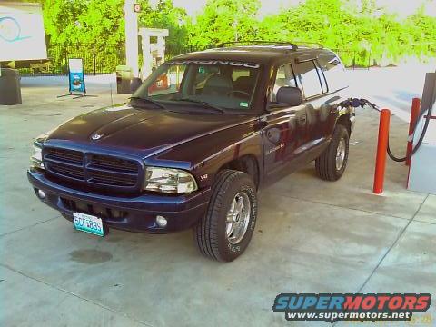 Dark blue Dodge Durango parked at a gas pump. License plate reads SCF 8995. 'DURANGO' is visible on the windshield