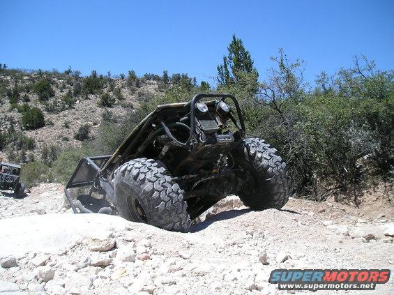 Rear view of a custom off-road buggy with large tires navigating a rocky incline