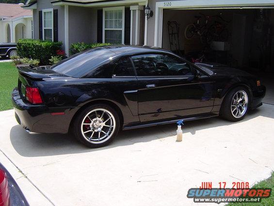 Black 2003 Ford Mustang parked in driveway, side view. Garage in background
