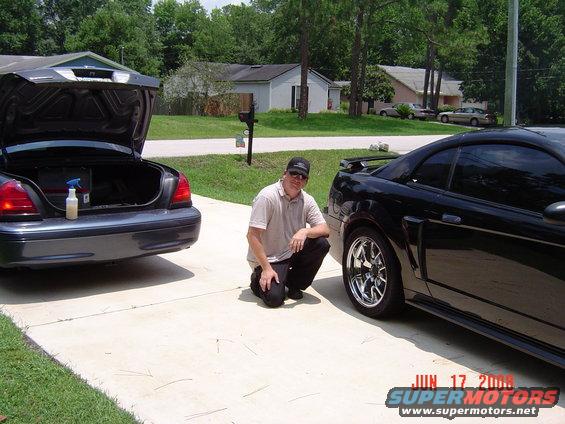 Black 2003 Ford Mustang with chrome wheels parked next to a sedan