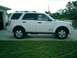 2008 Ford Escape - Side view of a white 2008 Ford Escape parked on a paved surface next to a lawn.