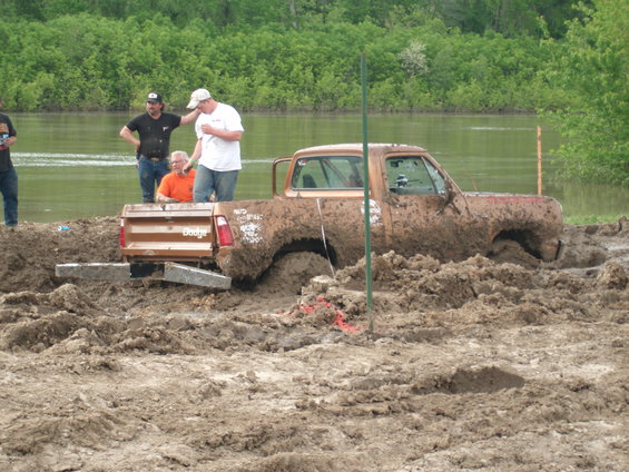 Brown pickup truck stuck in mud, rear Dodge badge visible