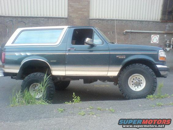 Side view of dark green and tan Ford Bronco SUV with aftermarket wheels