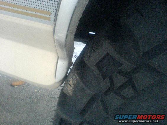 Close-up of a tire tread and a white fender flare with a textured decal