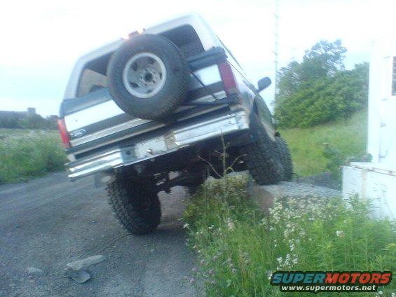 1985 Ford Bronco with spare tire mounted on rear, tilted on uneven ground