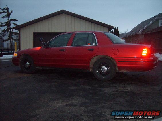Side view of a red 2000 Ford Crown Victoria parked in front of a garage