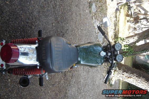Overhead view of a vintage green Yamaha motorcycle with black seat and red rear shocks
