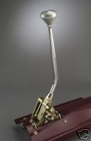 Close-up of a chrome and brass manual transmission shifter assembly mounted on a dark red surface