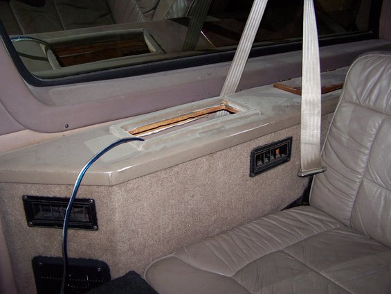 Interior console with open slot and air vents next to beige leather seat and seatbelt