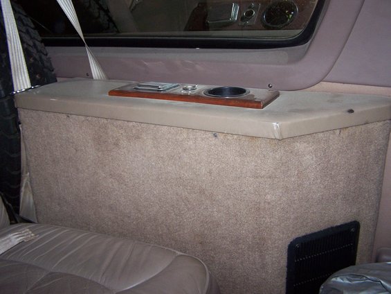 Interior console with cup holder, storage compartment, and a spare tire visible on the left