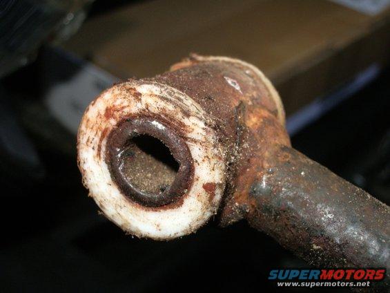 Close-up of a rusted metal component with a white bushing, showing wear and corrosion
