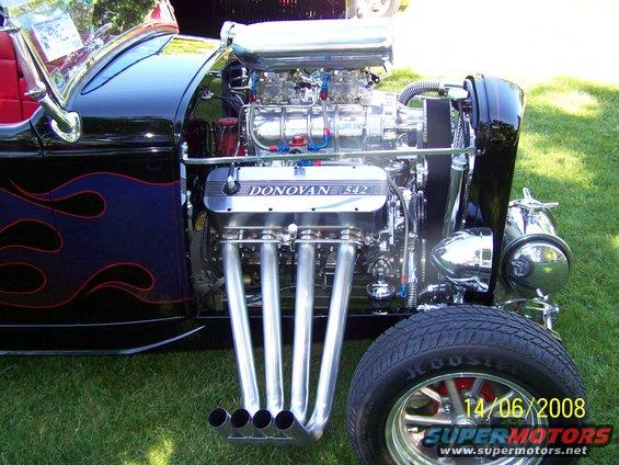 Hot rod with blown Donovan 542 engine, flame graphics on fender, and side pipes