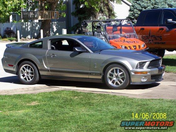 Silver Ford Mustang GT500 parked in driveway with an orange UTV and orange truck behind it