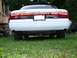 1997 Mercury Grand Marquis - The rear of a 1997 Mercury Grand Marquis is shown parked on grass next to a large yellow vehicle.